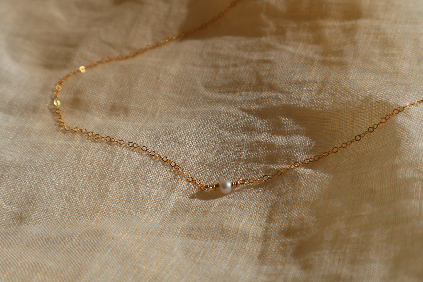 Gold necklace on a textured beige fabric background
