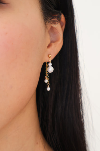 Close-up of an ear with a pearl earring against a neutral background