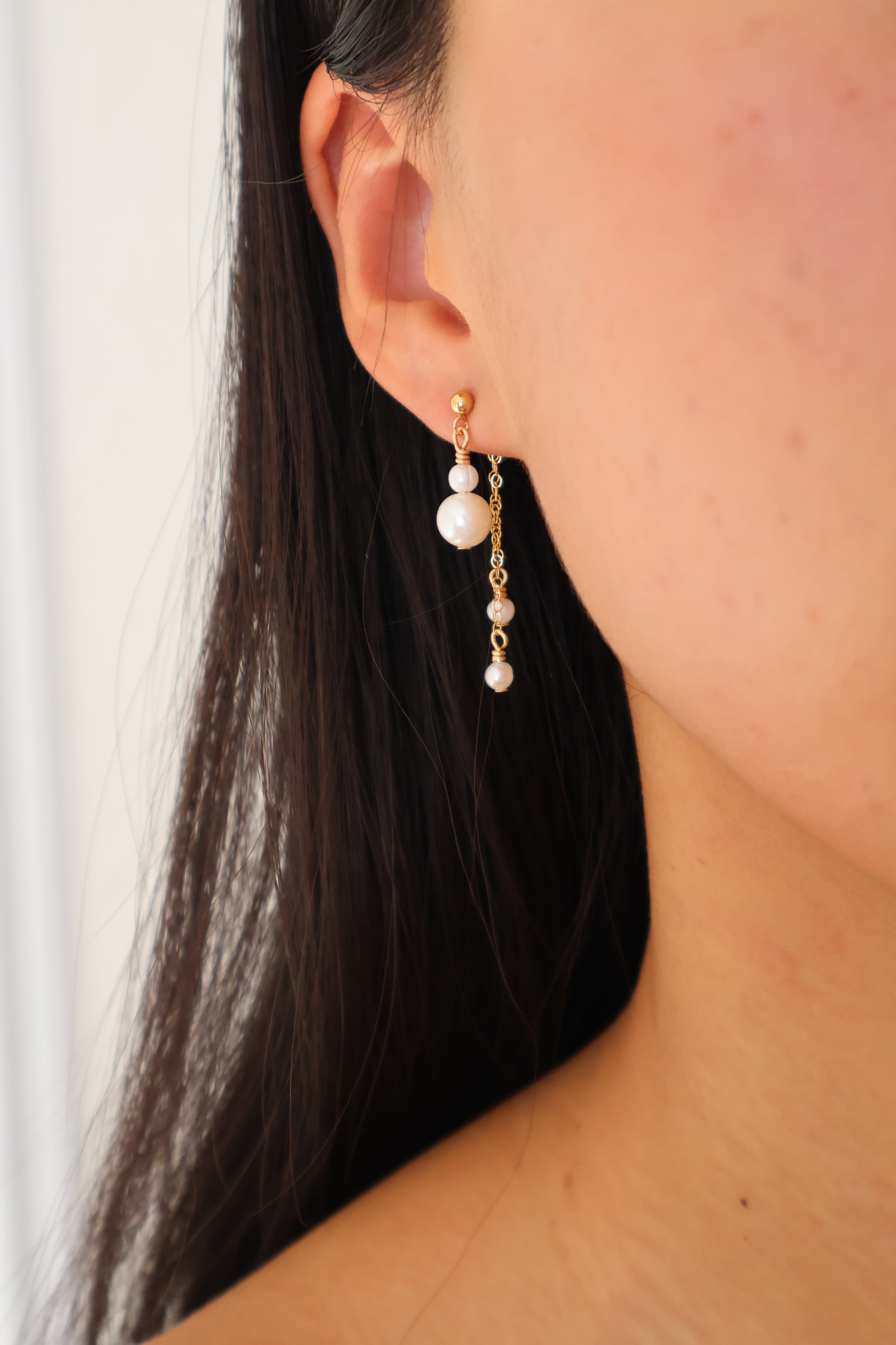 Close-up of an ear wearing a pearl earring with a blurred background