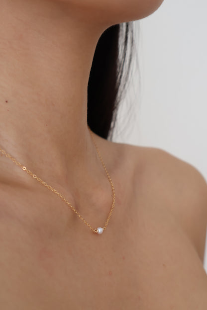 Gold chain on a person's neck with a plain background
