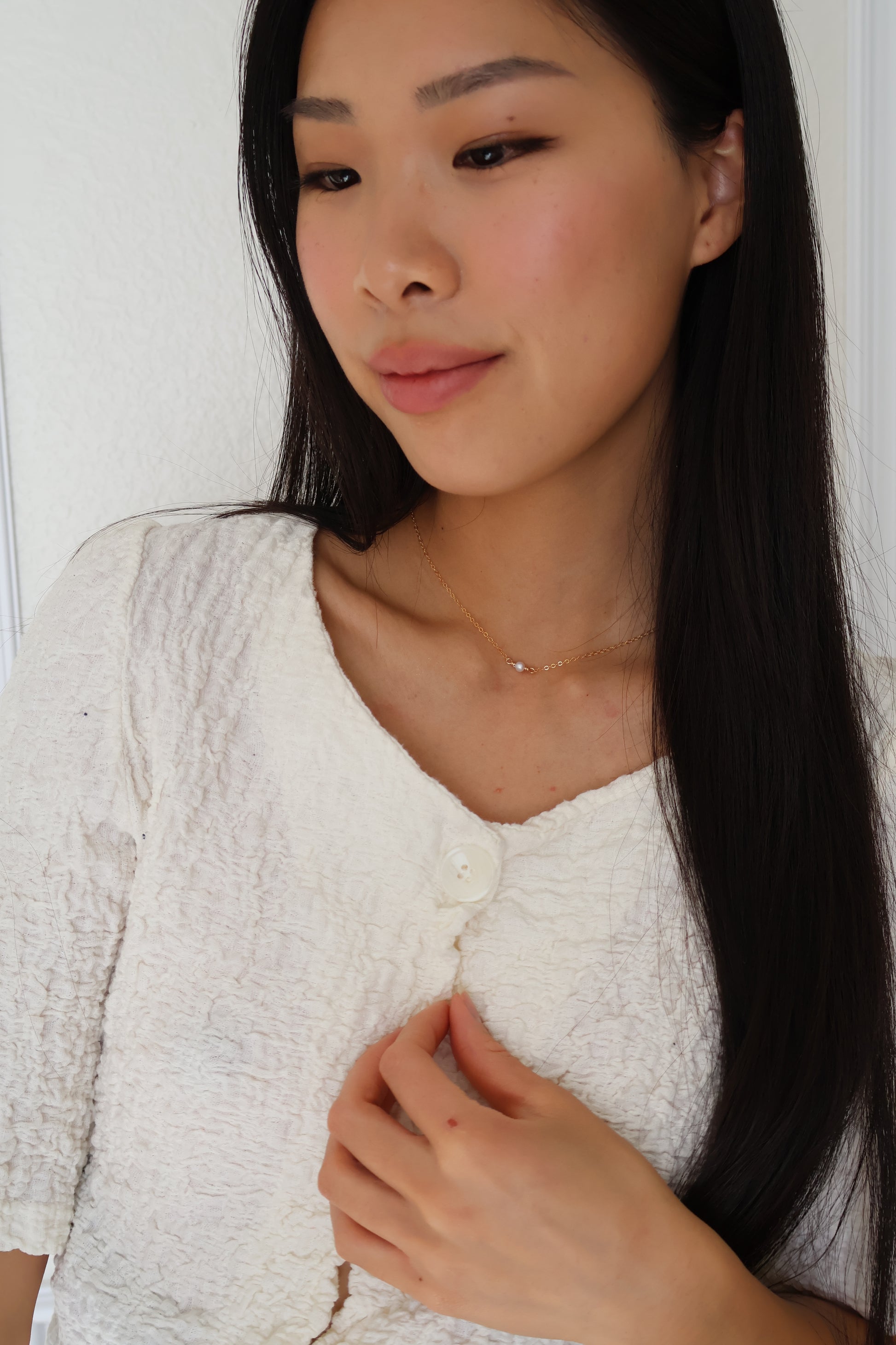 woman wearing dainty gold chain with a pearl pendant