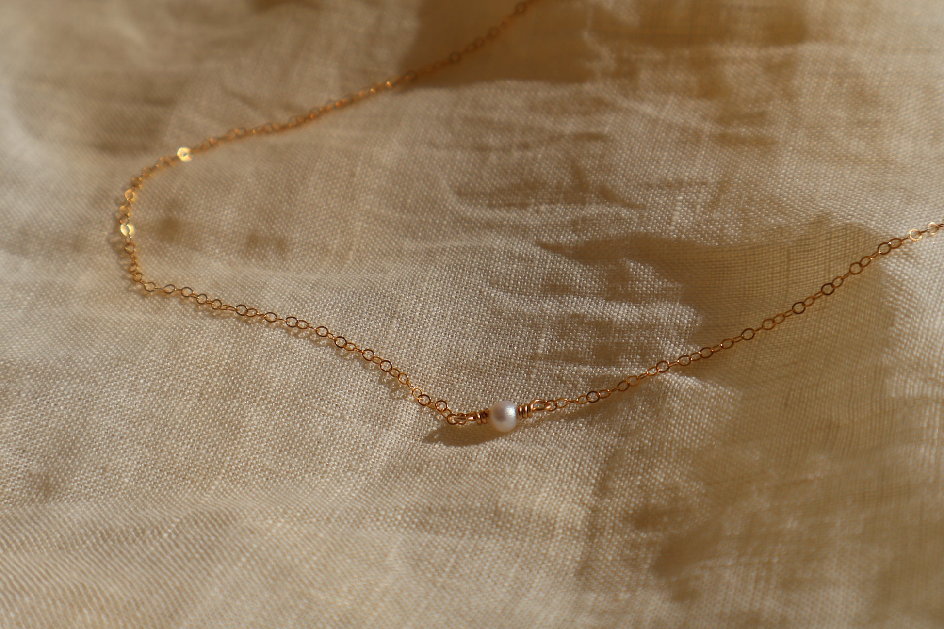 Gold necklace on a textured beige fabric background
