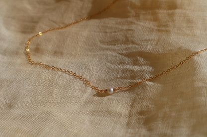 Gold necklace on a textured beige fabric background